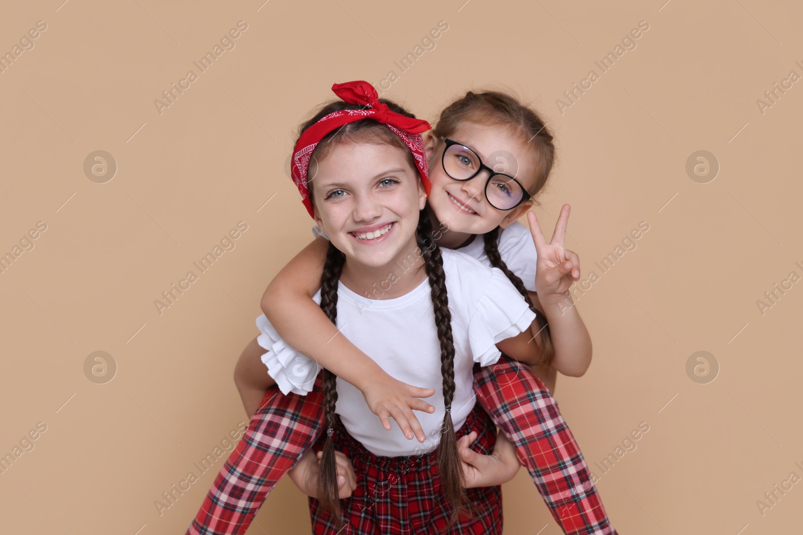 Photo of Portrait of cute little sisters on beige background