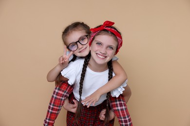 Photo of Portrait of cute little sisters on beige background