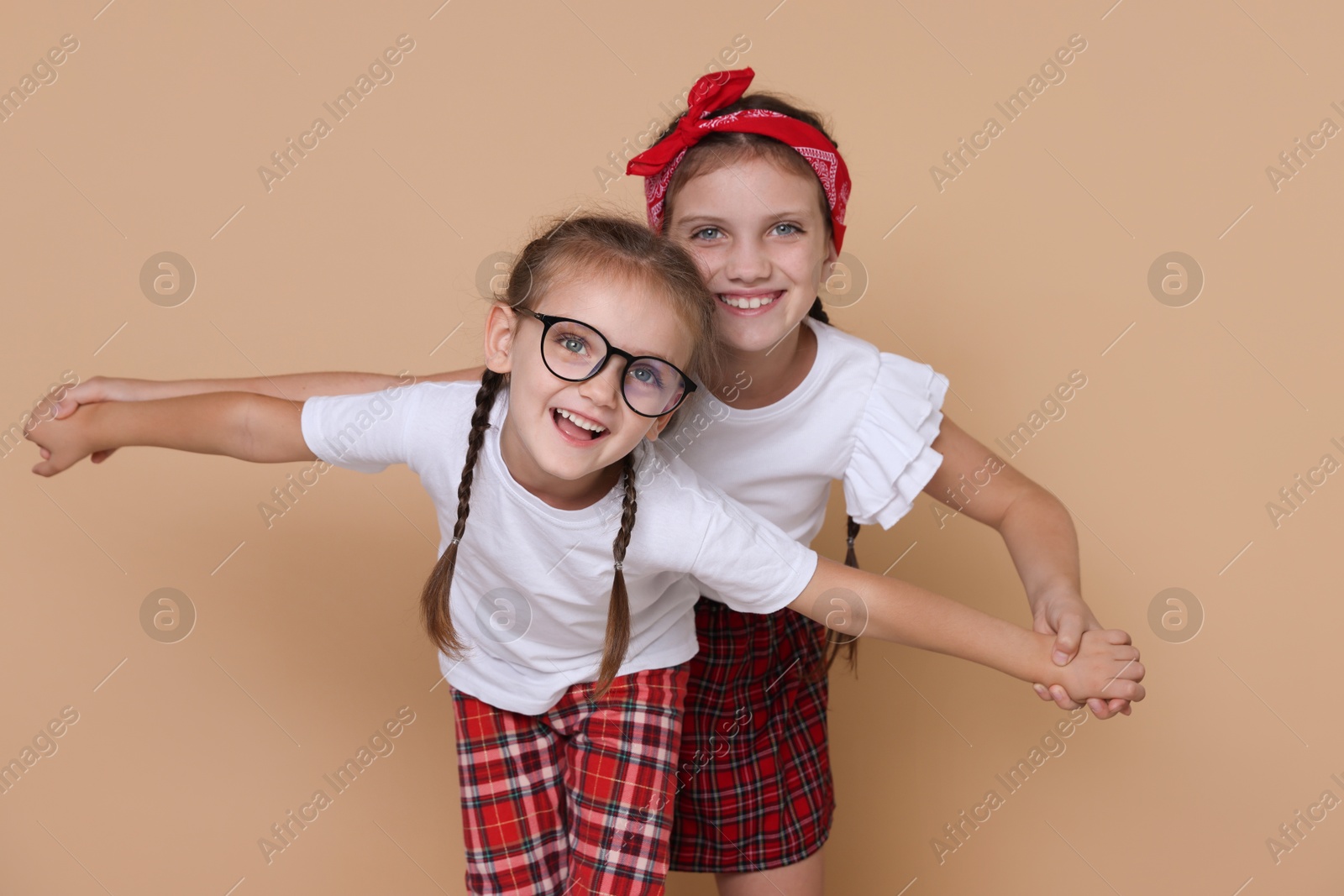 Photo of Portrait of cute little sisters on beige background