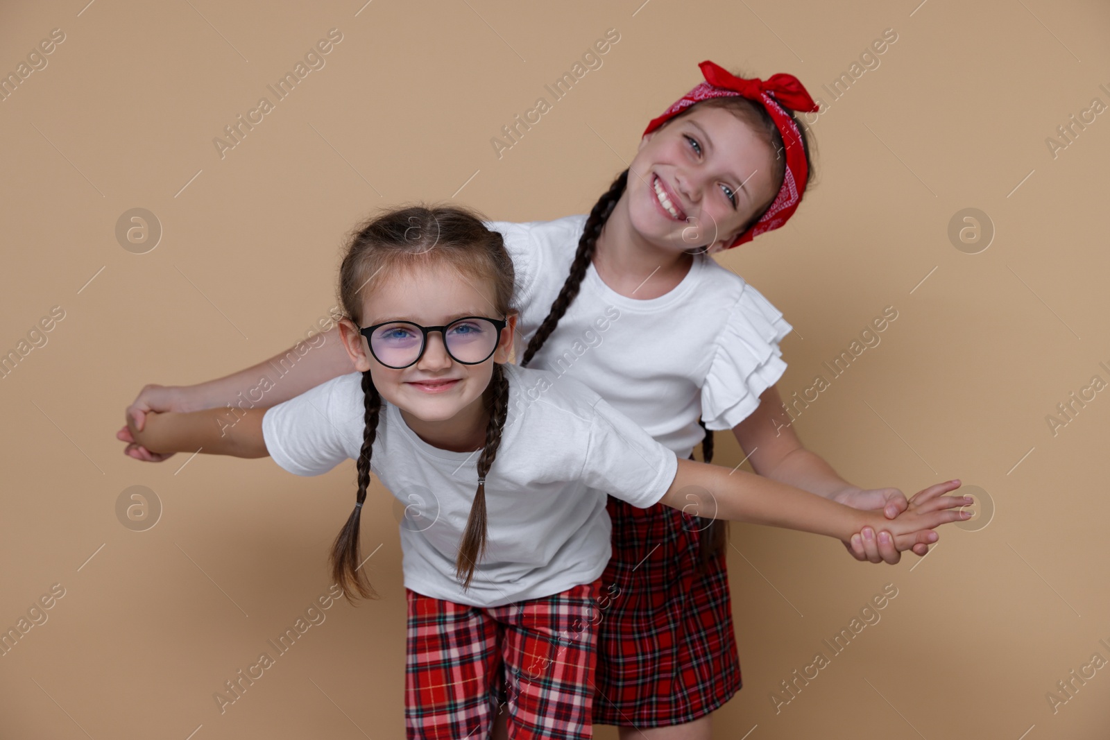 Photo of Portrait of cute little sisters on beige background