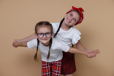 Portrait of cute little sisters on beige background