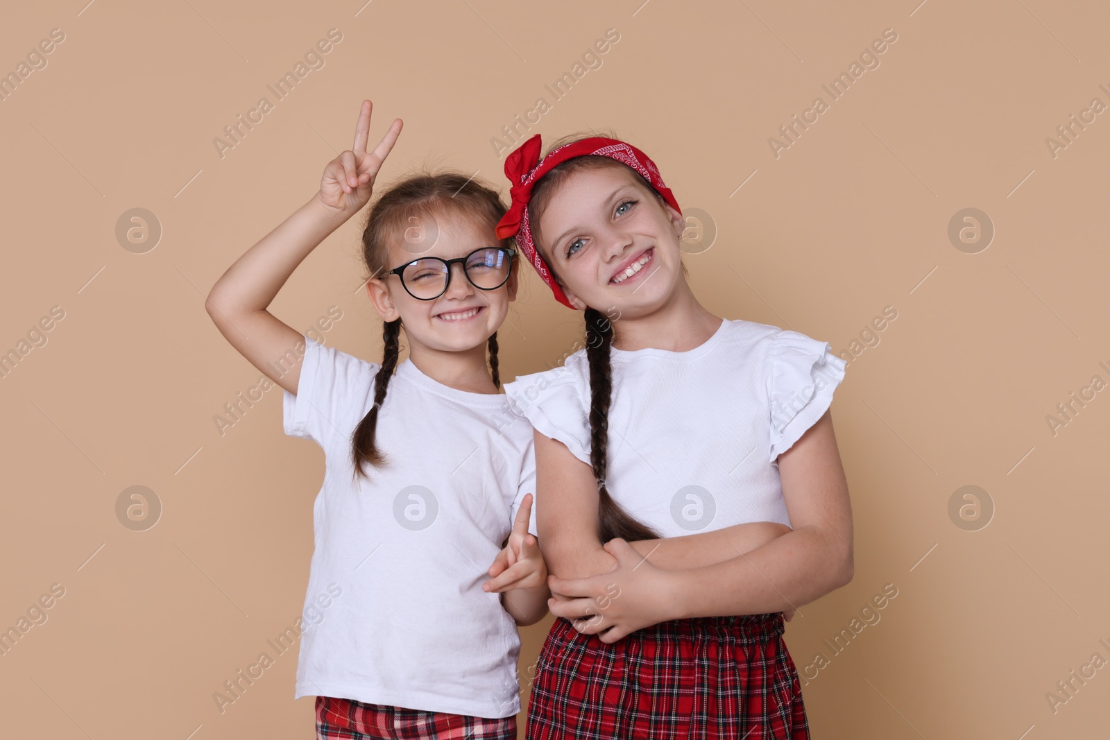 Photo of Portrait of cute little sisters on beige background