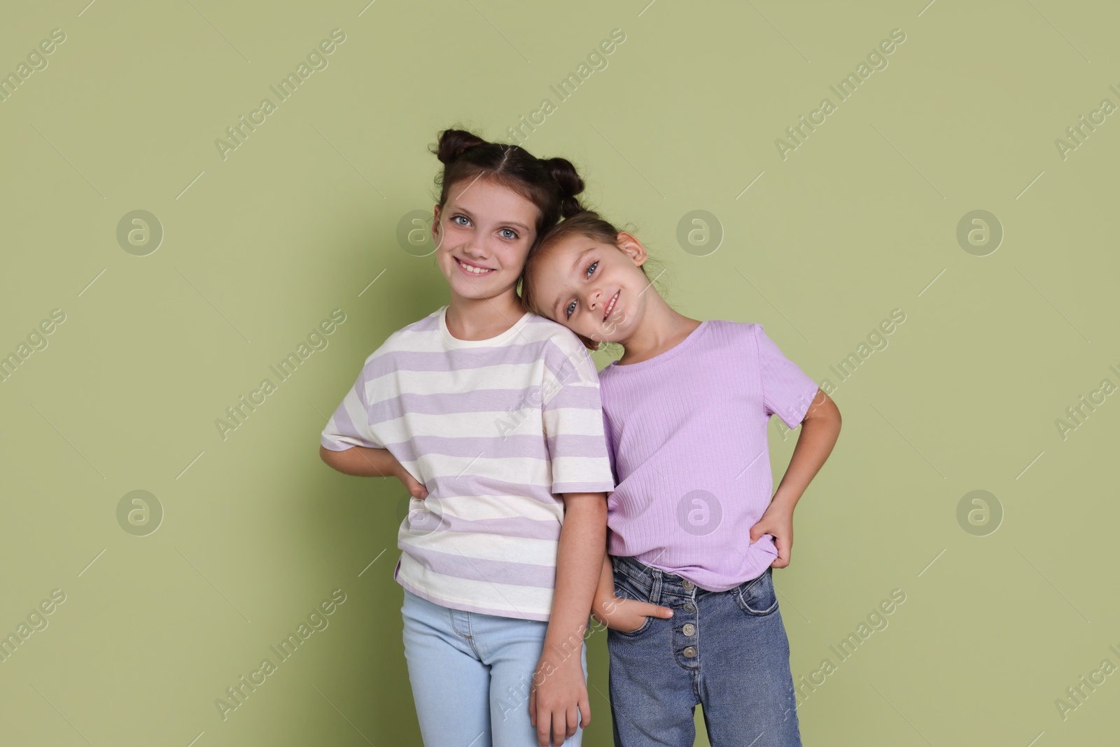 Photo of Portrait of cute little sisters on light green background