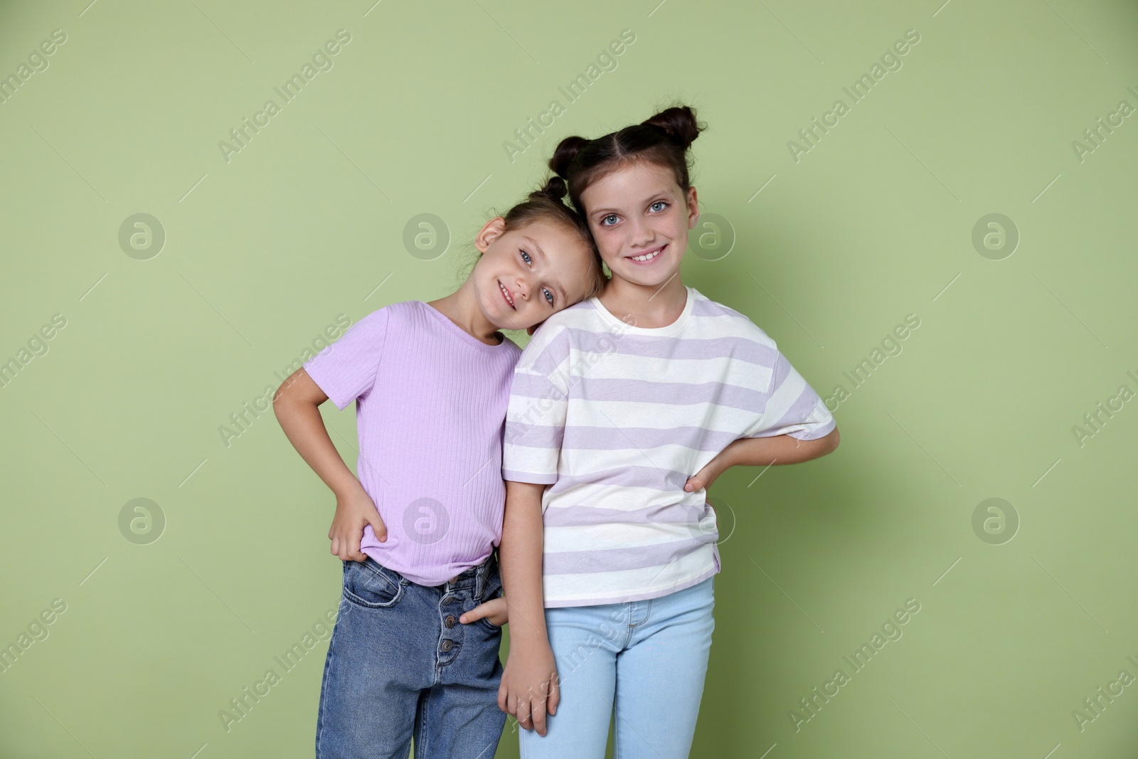 Photo of Portrait of cute little sisters on light green background