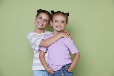 Photo of Portrait of cute little sisters on light green background