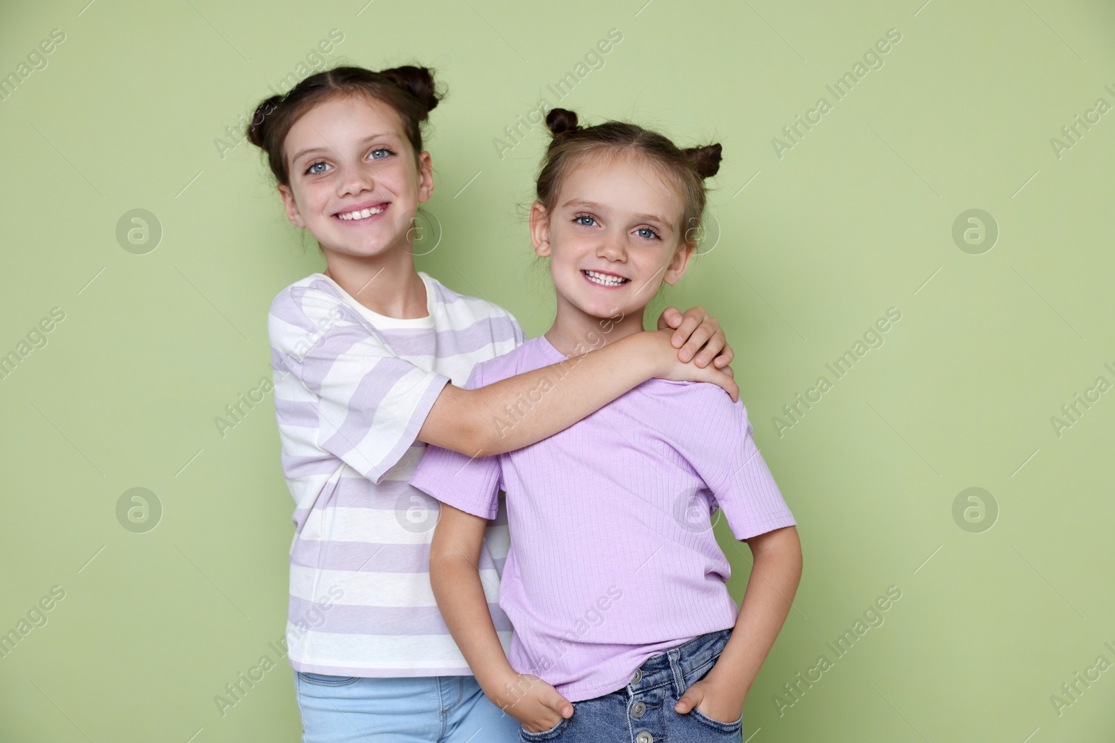 Photo of Portrait of cute little sisters on light green background