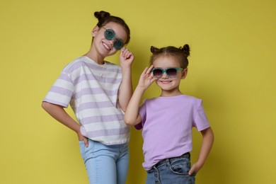 Portrait of cute little sisters on yellow background