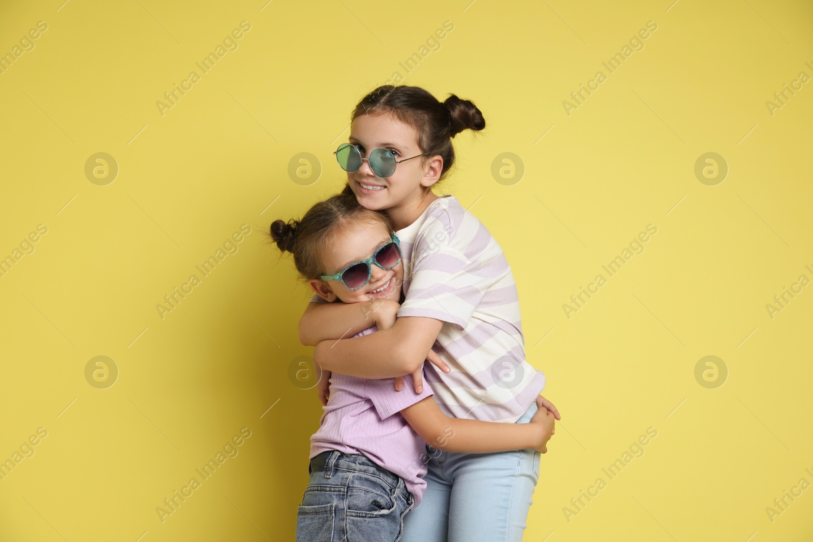 Photo of Portrait of cute little sisters on yellow background