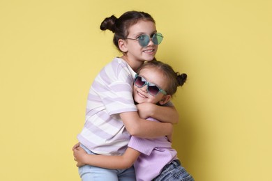 Photo of Portrait of cute little sisters on yellow background