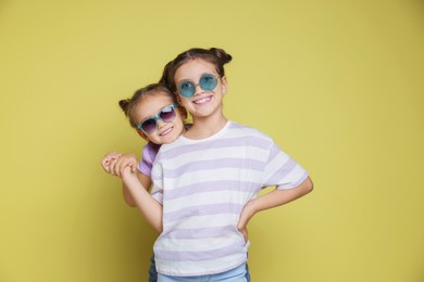 Portrait of cute little sisters on yellow background