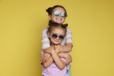 Portrait of cute little sisters on yellow background