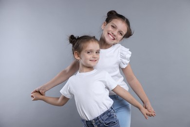 Photo of Portrait of cute little sisters on grey background