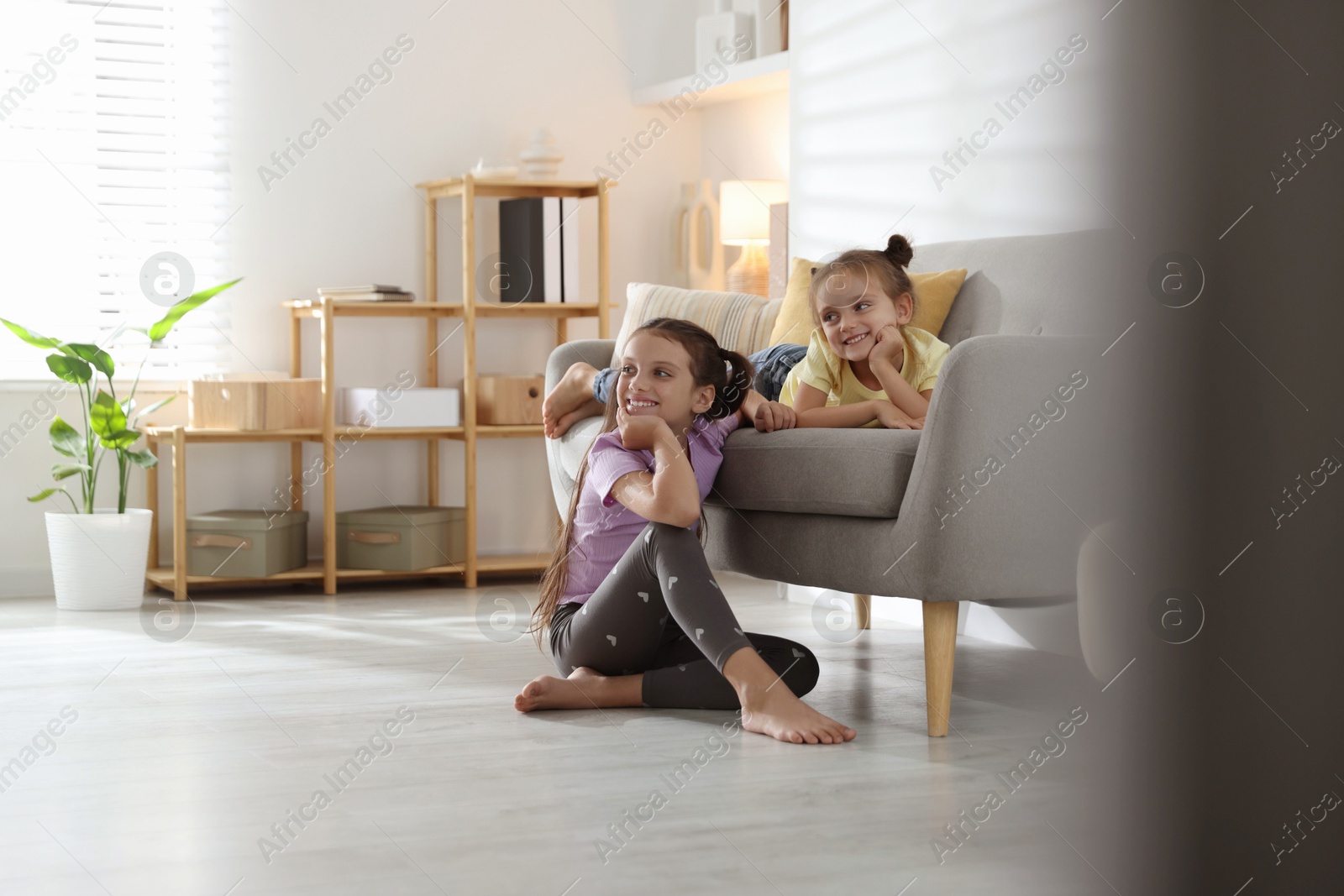 Photo of Cute little sisters spending time together at home, space for text