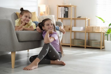 Photo of Cute little sisters spending time together at home, space for text