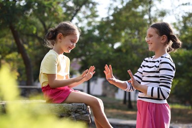 Cute little sisters playing clapping game in park