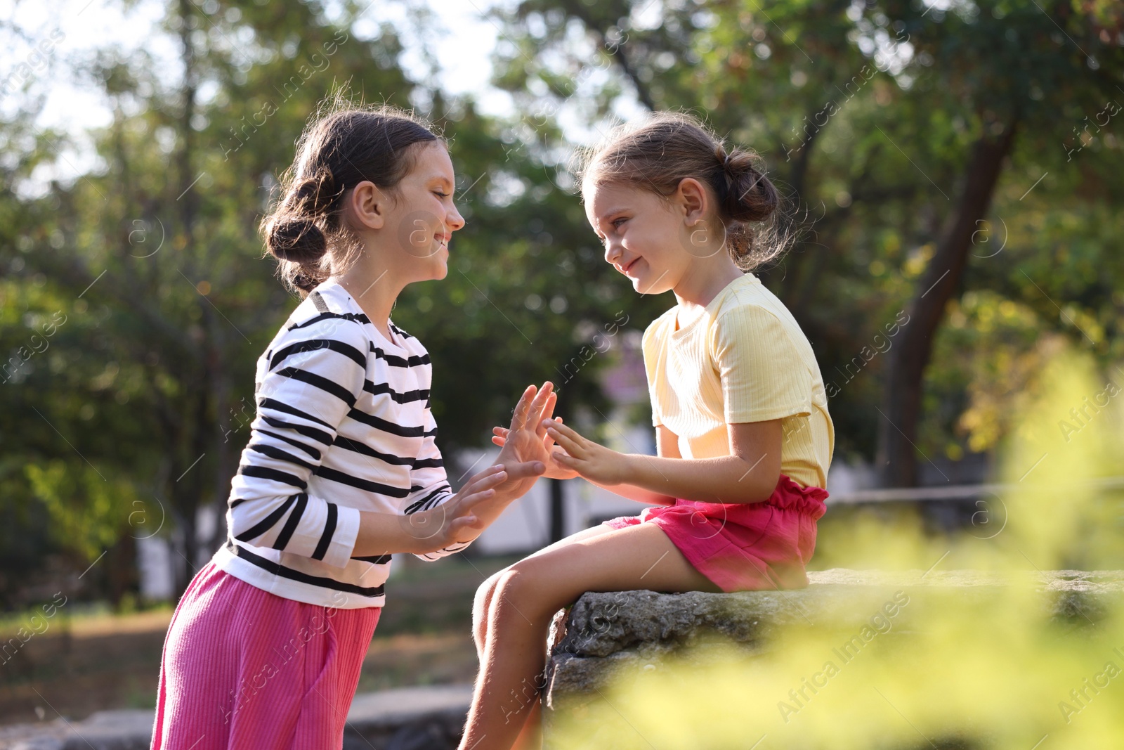 Photo of Cute little sisters playing clapping game in park