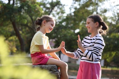 Photo of Cute little sisters playing clapping game in park