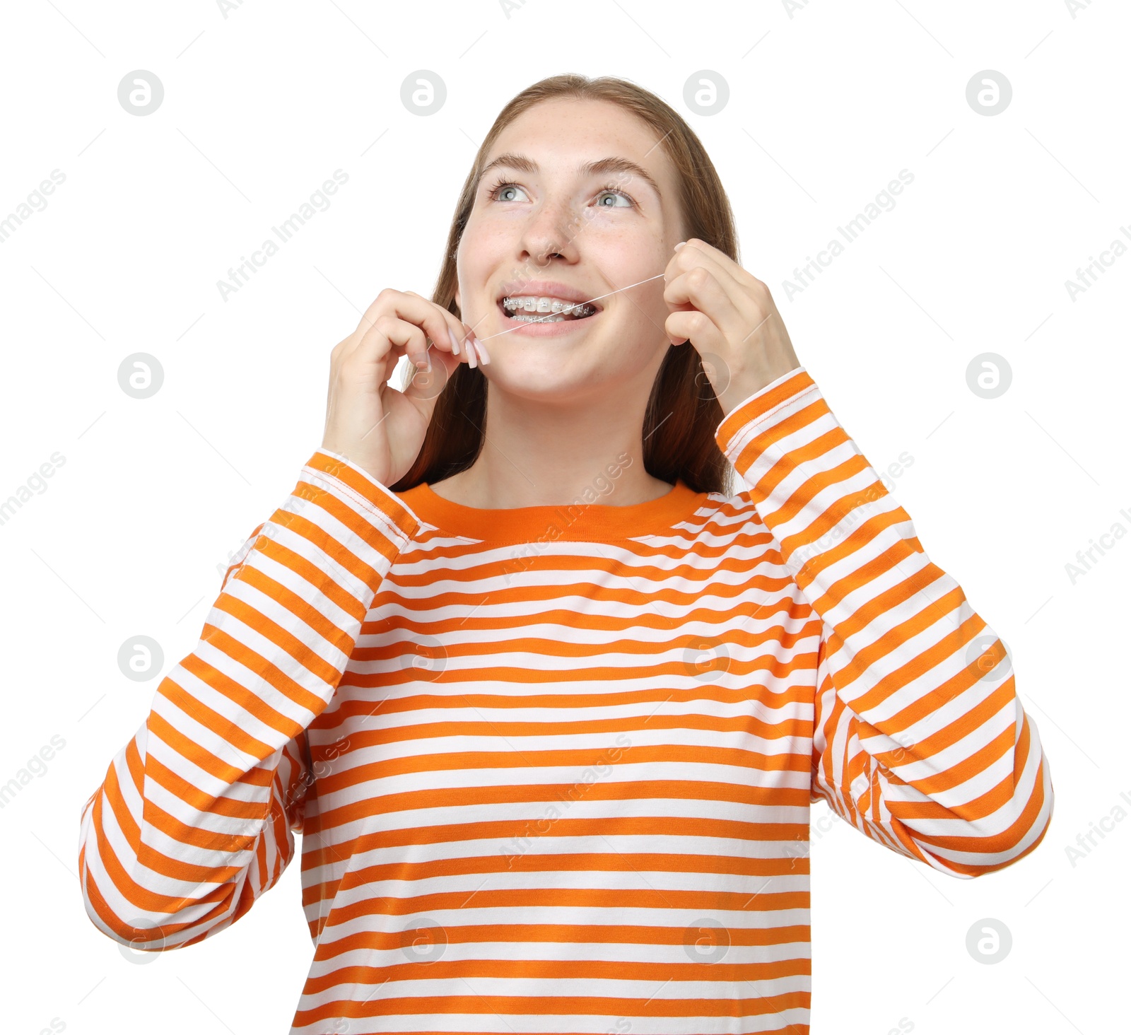 Photo of Smiling girl with braces cleaning teeth with dental floss on white background