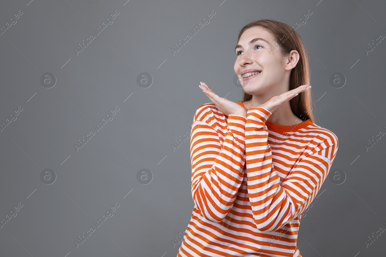 Photo of Smiling girl with braces on grey background, space for text