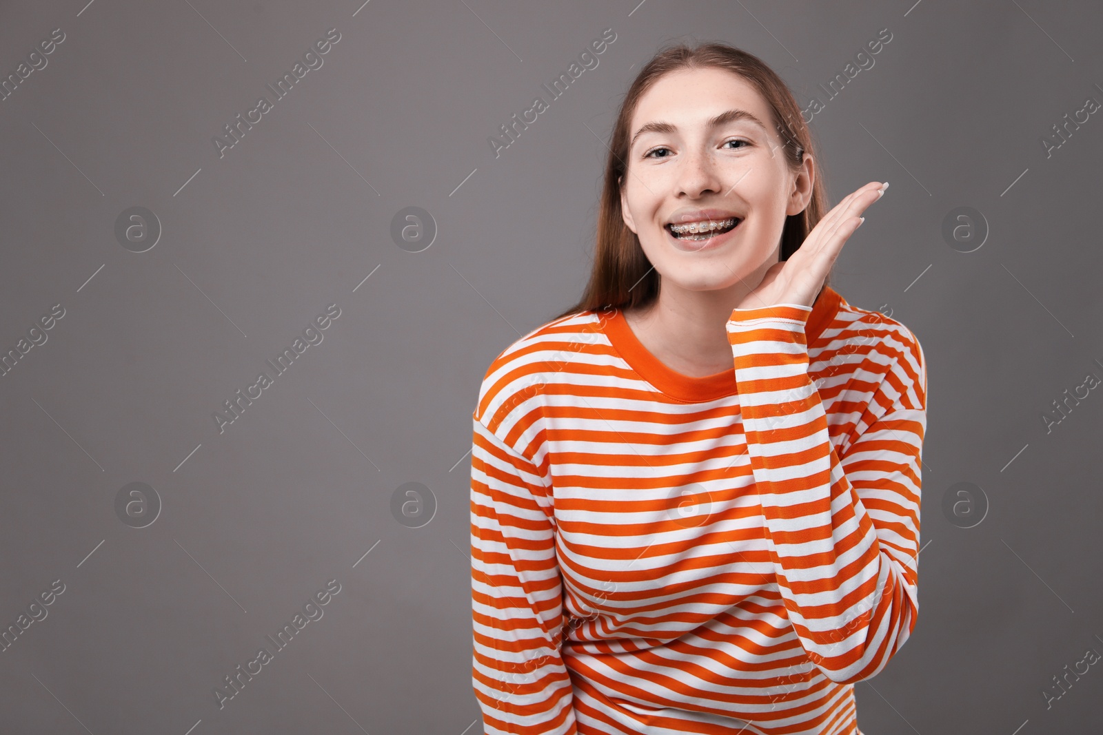 Photo of Smiling girl with braces on grey background, space for text