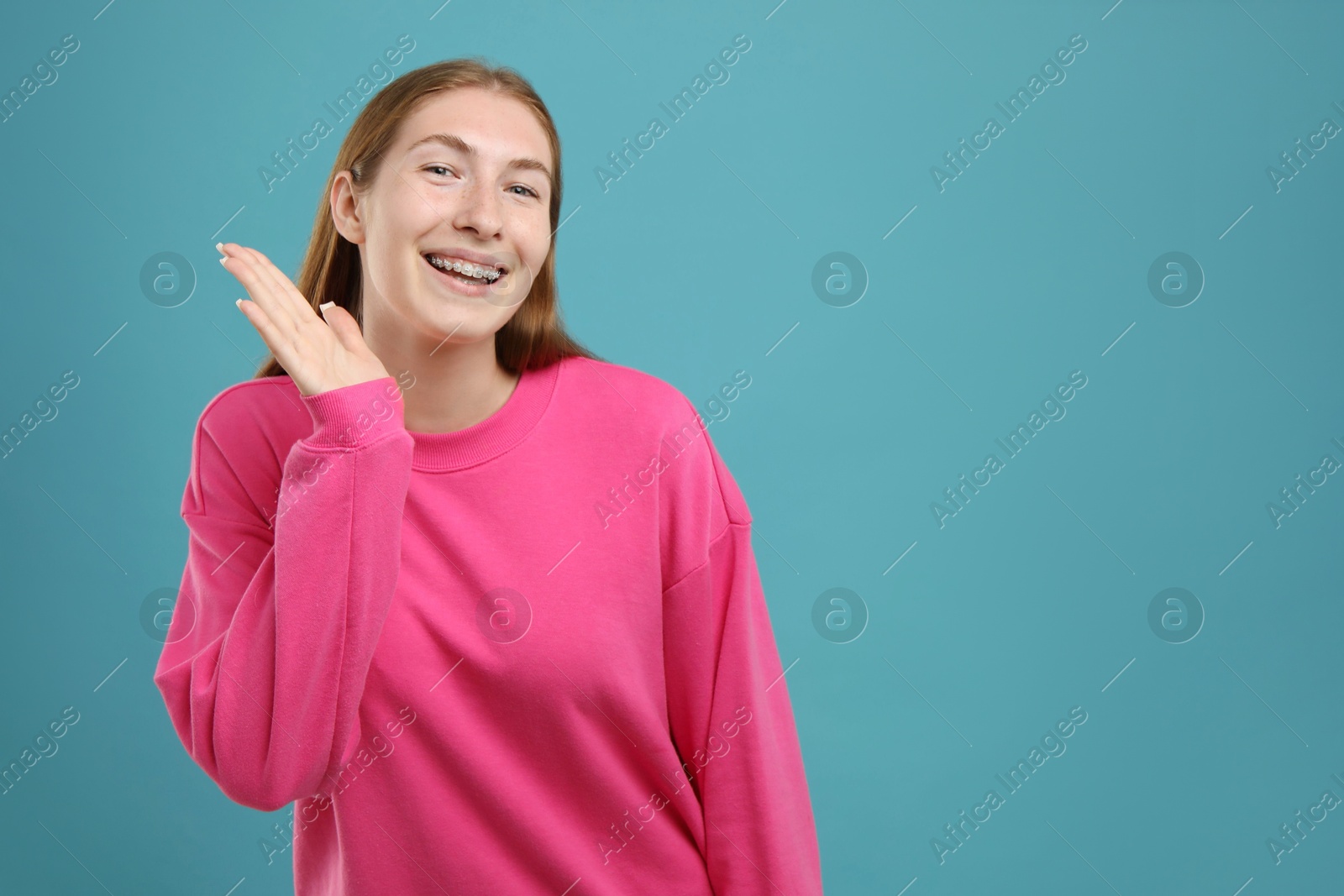 Photo of Smiling girl with braces on light blue background, space for text