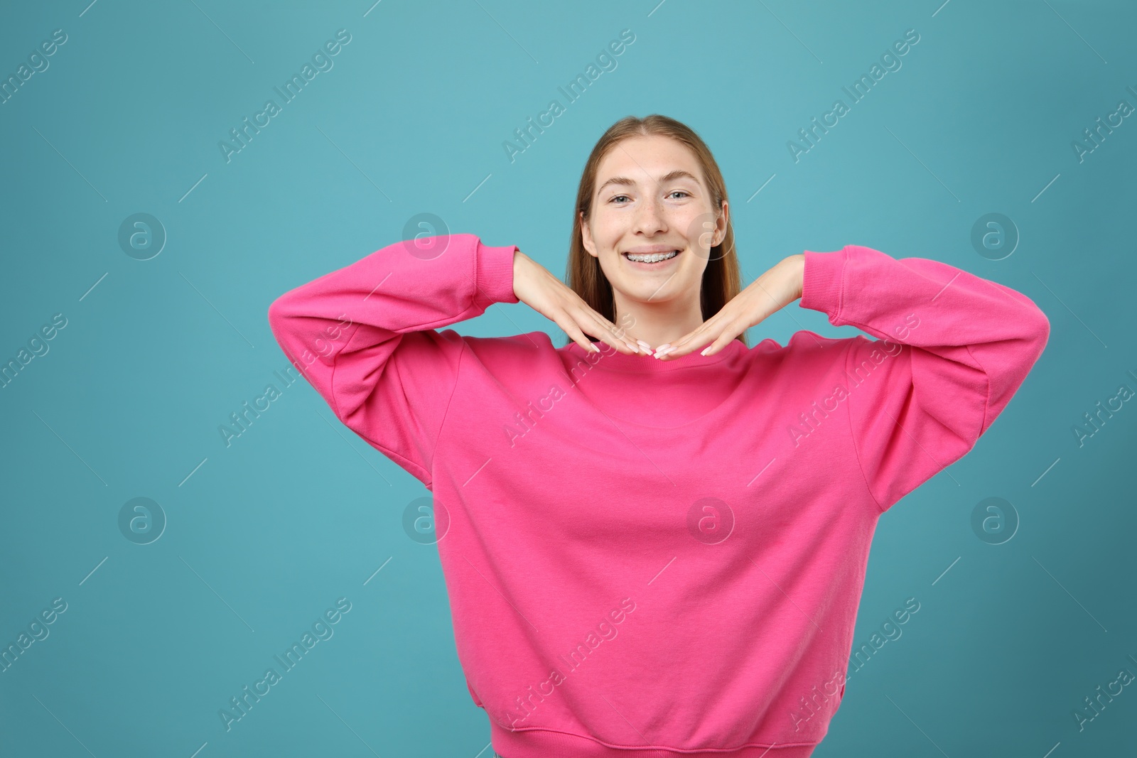 Photo of Smiling girl with braces on light blue background