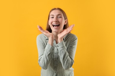 Photo of Smiling girl with braces on orange background