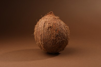 One whole coconut in shell on brown background