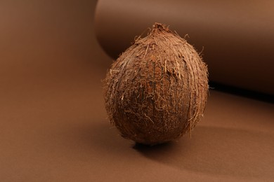 One whole coconut in shell on brown background, space for text