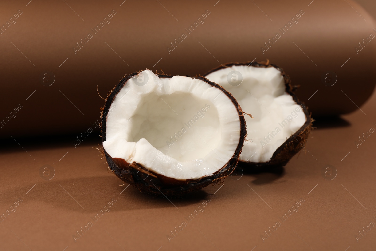 Photo of Halves of cracked coconut on brown background