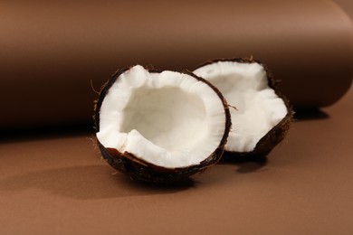 Photo of Halves of cracked coconut on brown background