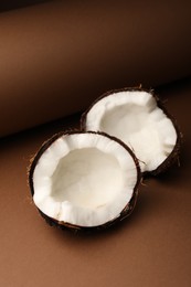 Photo of Halves of cracked coconut on brown background