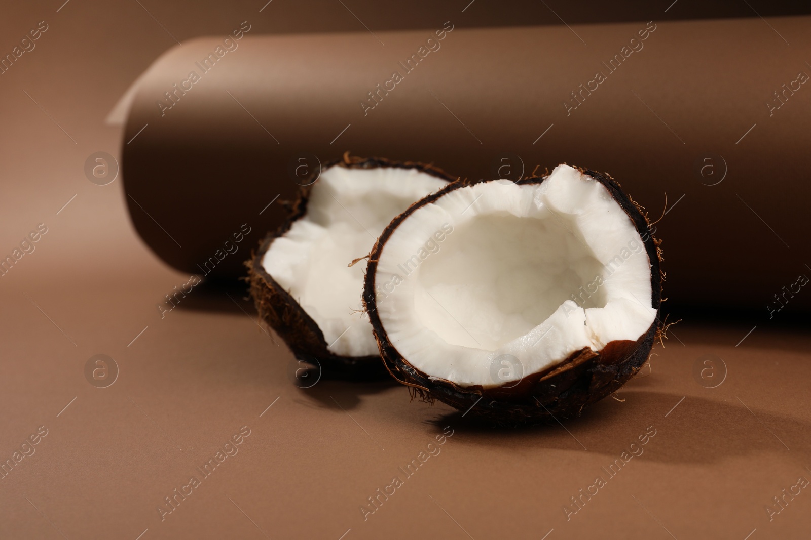 Photo of Halves of cracked coconut on brown background