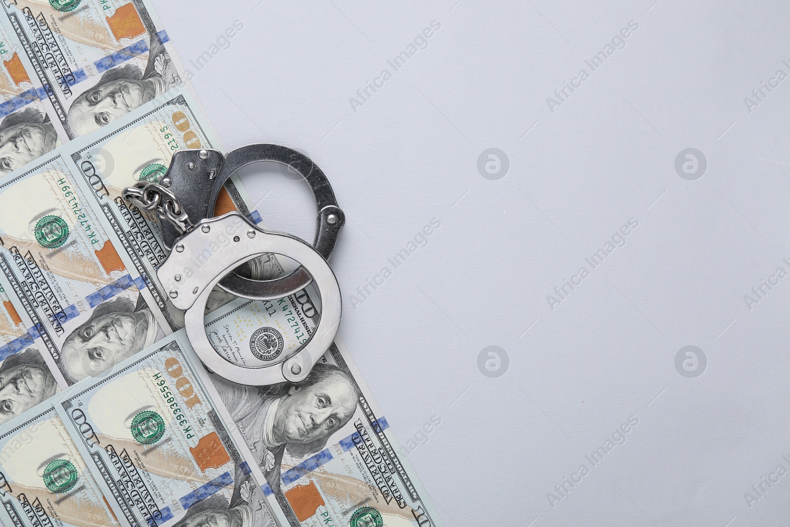 Photo of Corruption concept. Handcuffs and dollar banknotes on grey background, top view. Space for text