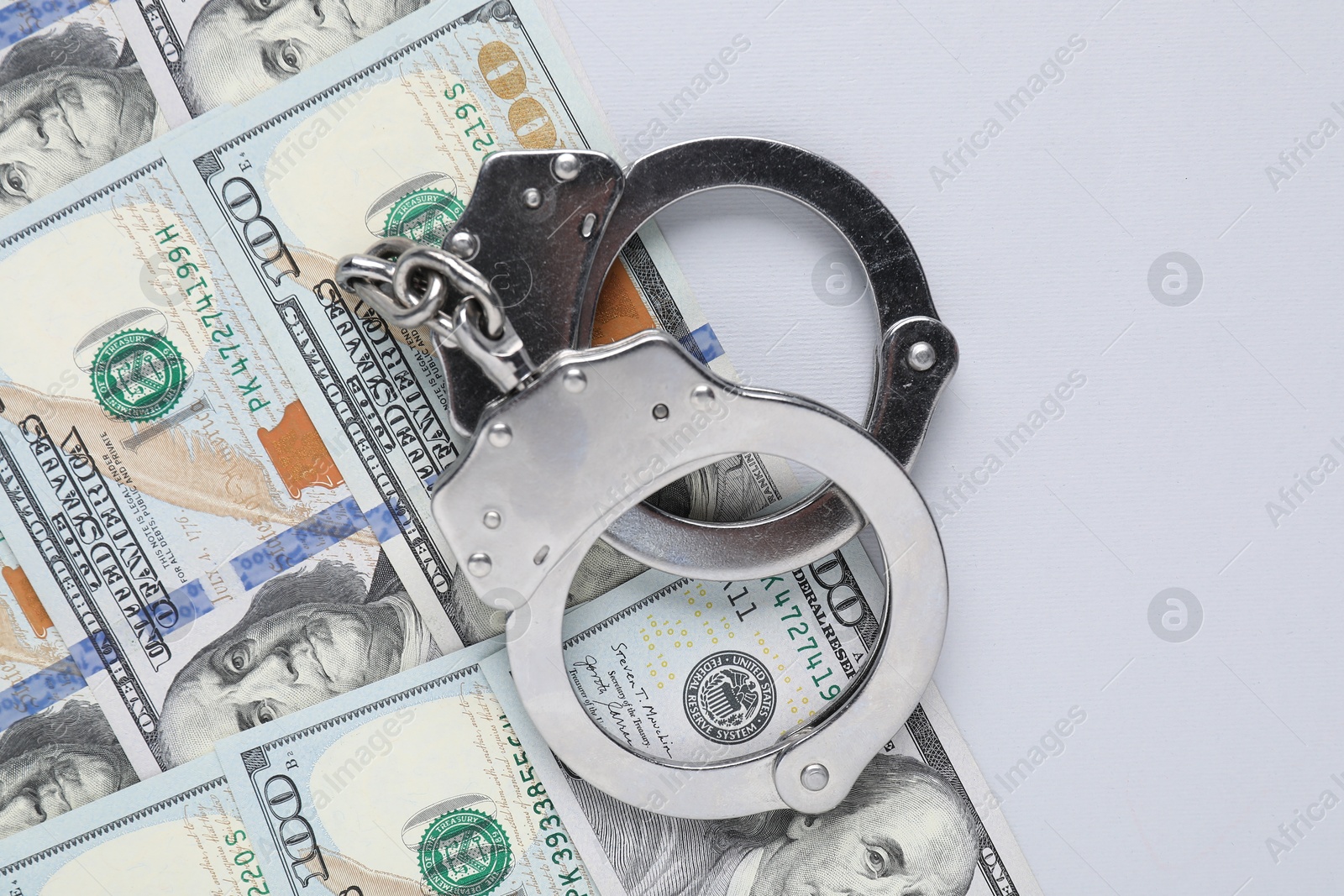 Photo of Corruption concept. Handcuffs and dollar banknotes on grey background, top view