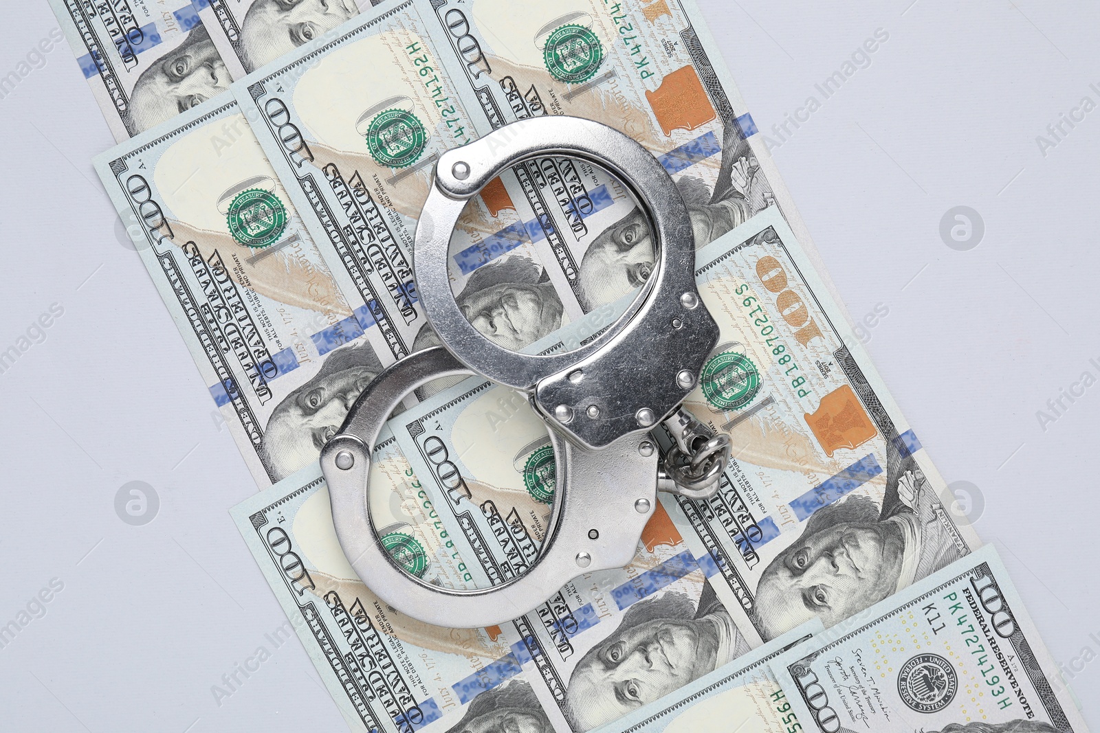 Photo of Corruption concept. Handcuffs and dollar banknotes on grey background, top view