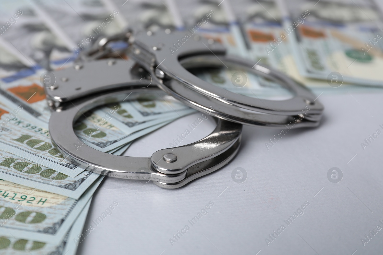 Photo of Corruption concept. Handcuffs and dollar banknotes on grey background, closeup