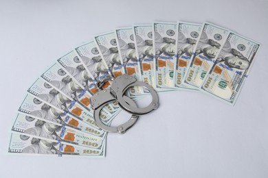 Photo of Corruption concept. Handcuffs and dollar banknotes on grey background