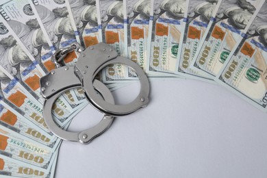 Photo of Corruption concept. Handcuffs and dollar banknotes on grey background, above view