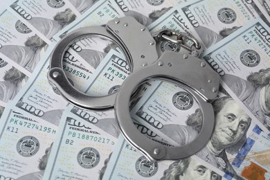 Corruption concept. Handcuffs on dollar banknotes, closeup