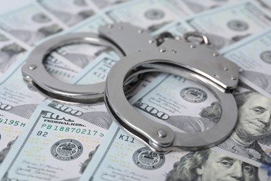 Corruption concept. Handcuffs on dollar banknotes, closeup