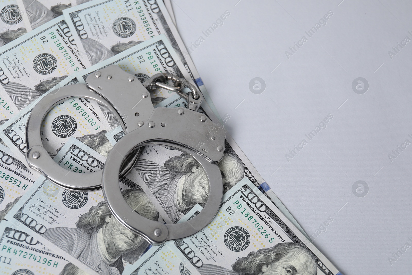 Photo of Corruption concept. Handcuffs and dollar banknotes on grey background, above view. Space for text