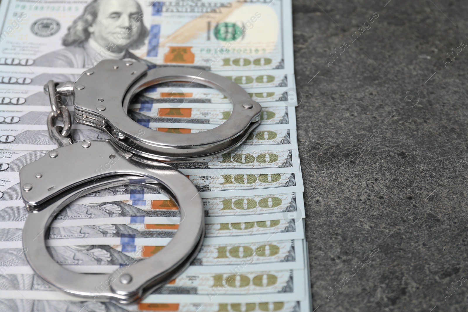 Photo of Corruption concept. Handcuffs and dollar banknotes on grey table, closeup