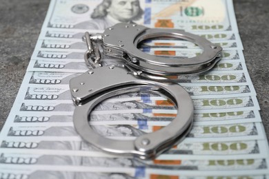 Photo of Corruption concept. Handcuffs and dollar banknotes on table, closeup