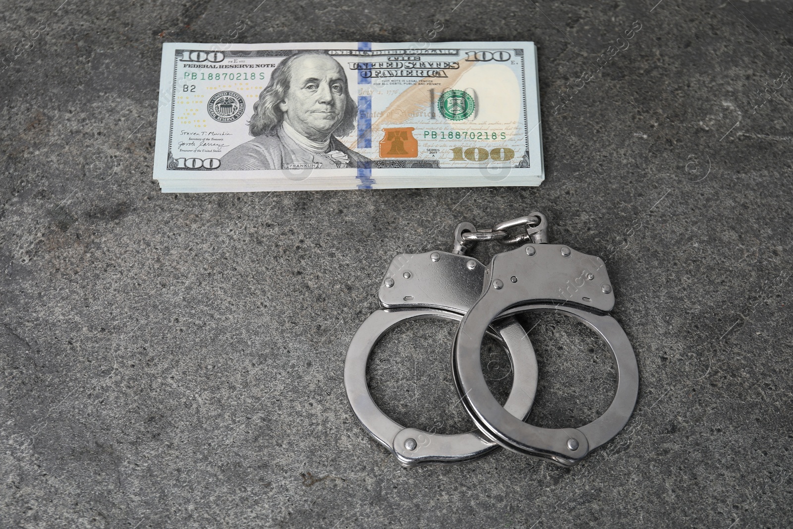 Photo of Corruption concept. Handcuffs and dollar banknotes on grey table, above view