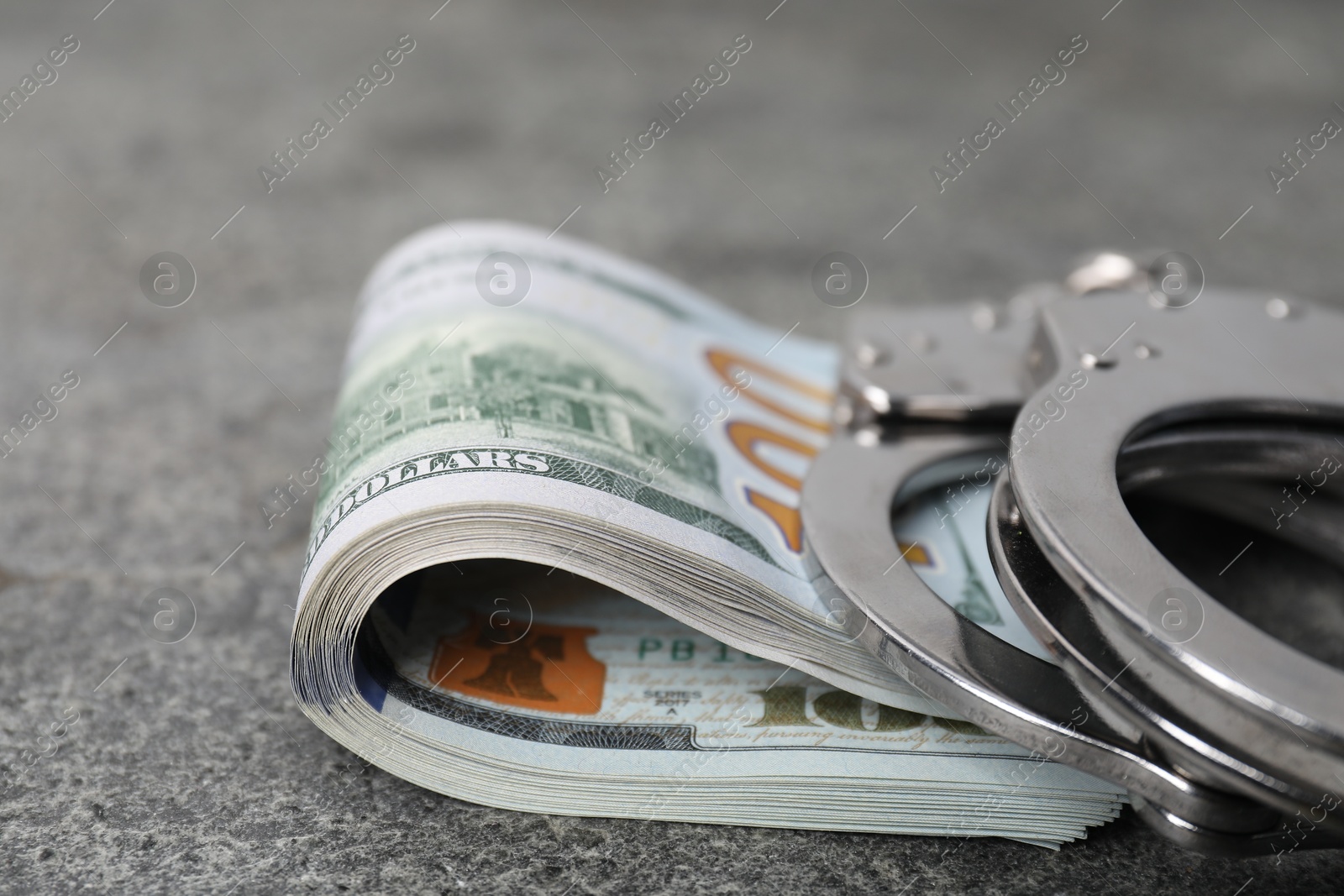 Photo of Corruption concept. Handcuffs and dollar banknotes on grey table, closeup