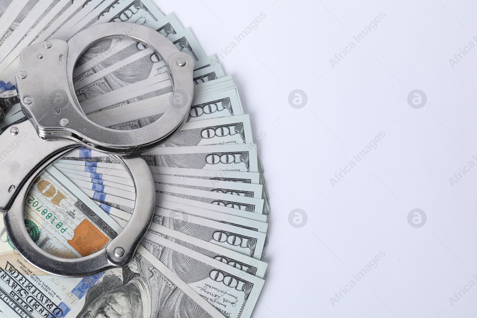 Photo of Corruption concept. Handcuffs and dollar banknotes on white background, top view. Space for text