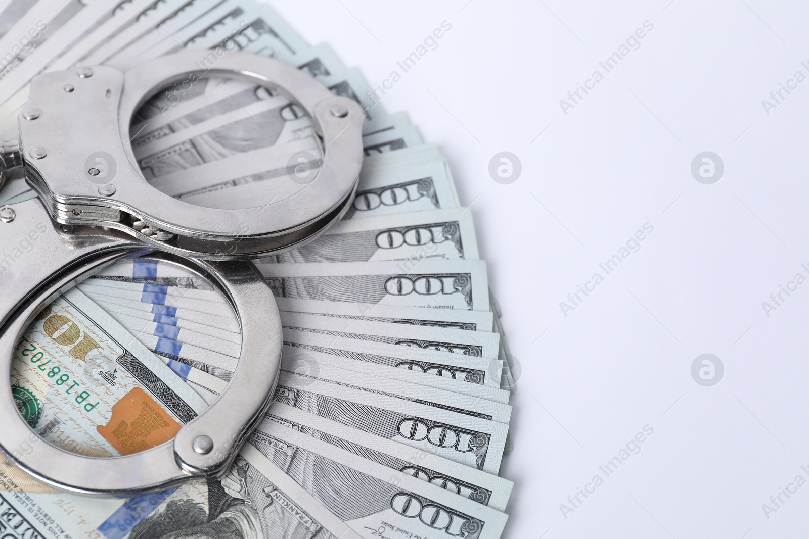 Photo of Corruption concept. Handcuffs and dollar banknotes on white background, closeup. Space for text