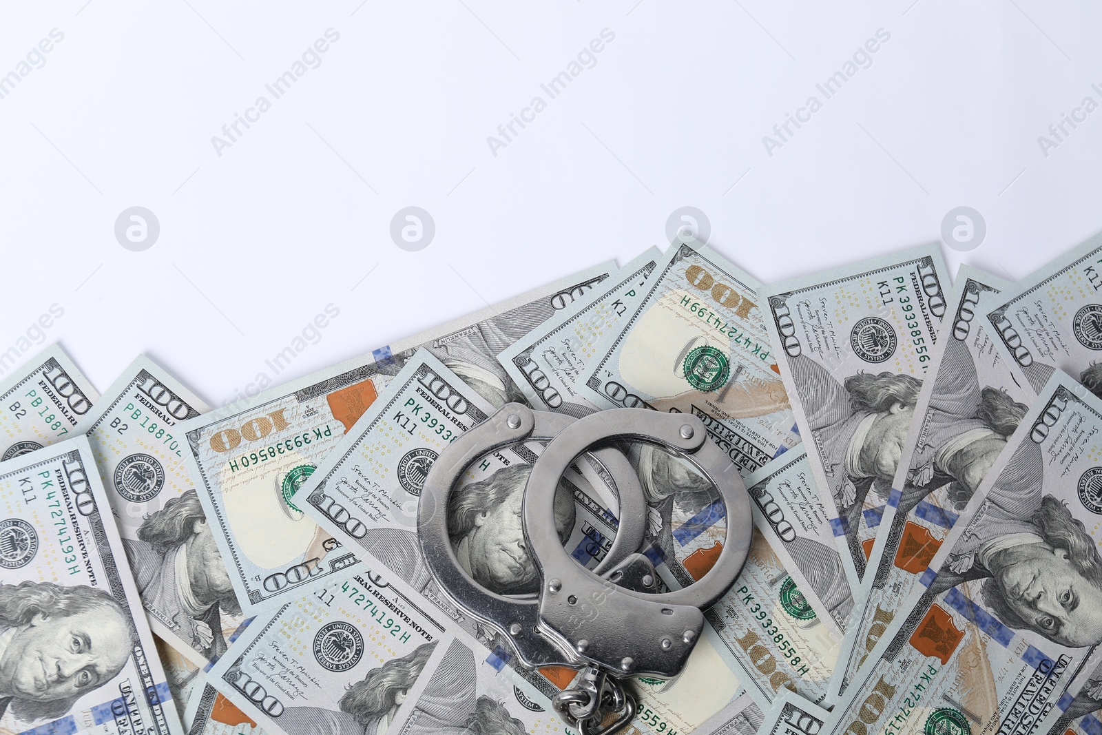 Photo of Corruption concept. Handcuffs and dollar banknotes on white background, top view