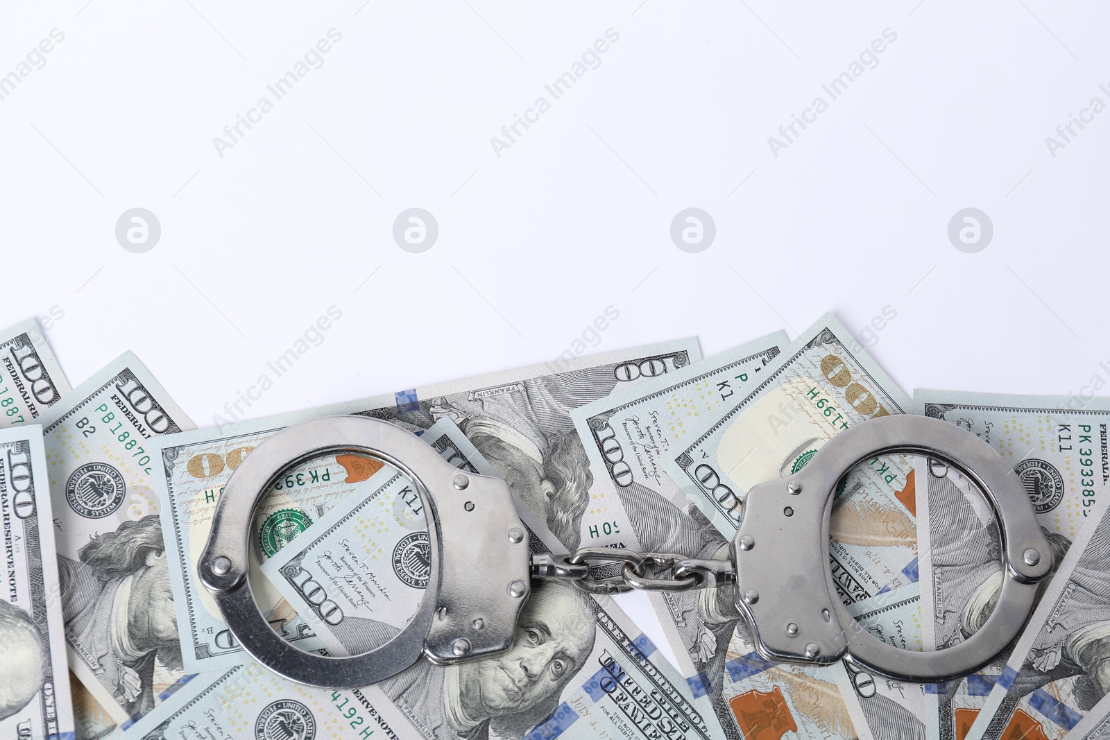 Photo of Corruption concept. Handcuffs and dollar banknotes on white background, top view